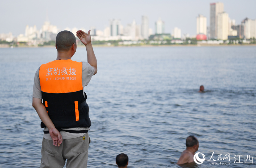 救援隊隊員正在示意一名向江中游去的市民往回游。 人民網 時雨攝