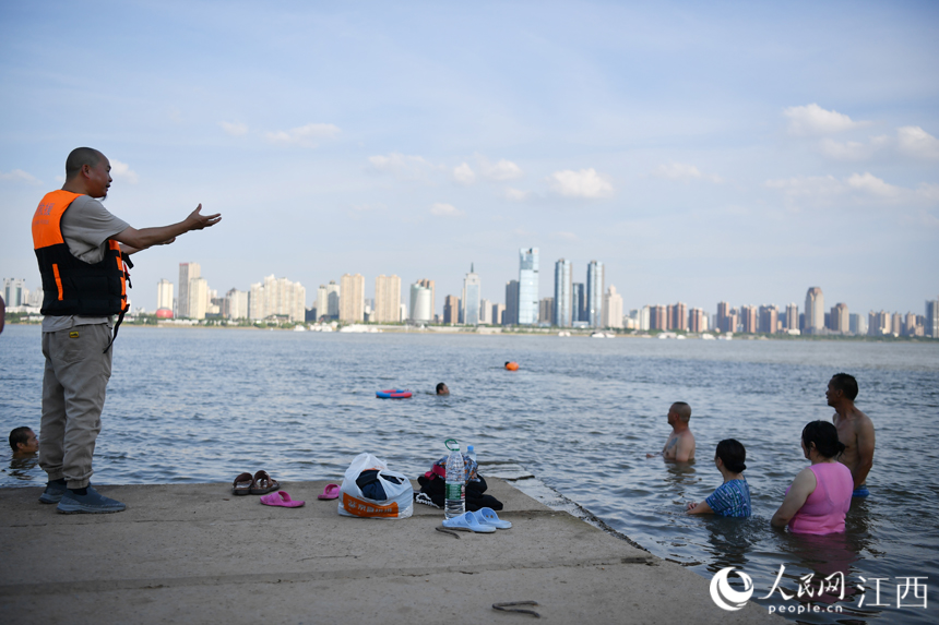 救援隊隊員告訴水中的市民：戲水納涼的同時不要忘記安全。 人民網 時雨攝