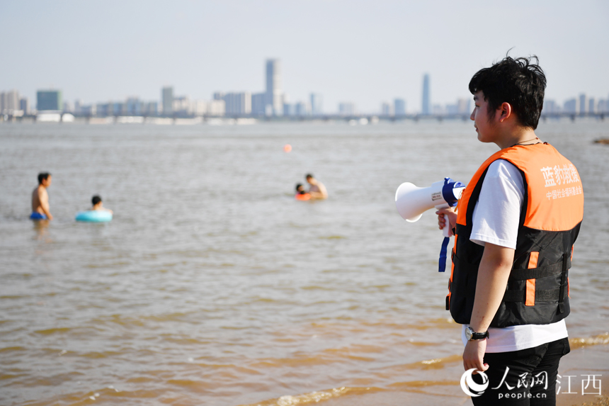 救援隊隊員用擴音喇叭提醒水中的市民注意安全。 人民網 時雨攝