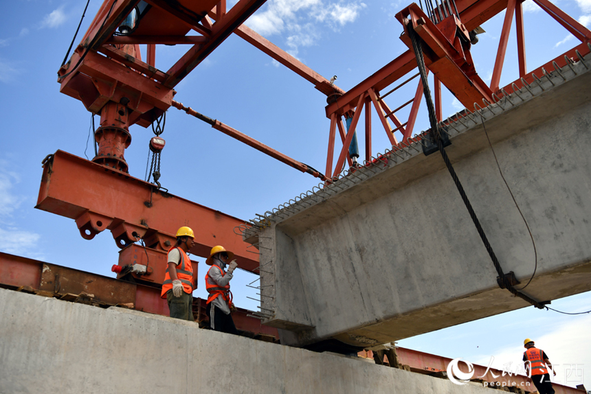 施工人員對架設的預制箱梁進行施工加固。 人民網 時雨攝