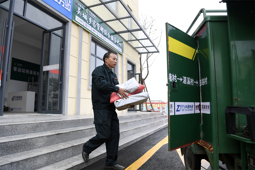 快遞員將包裹抱至快遞車上，準備送到村民家中。 周亮攝