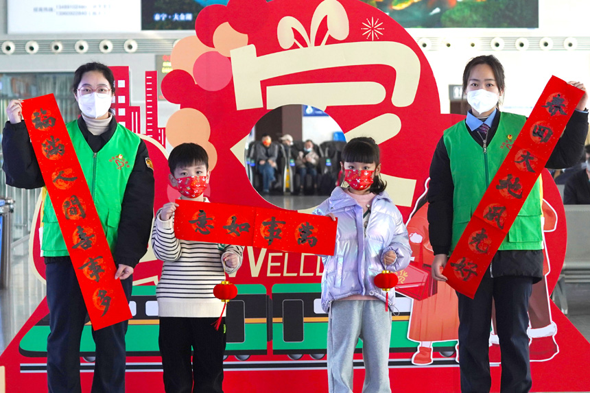 南鐵永安車務段青年志愿者與兒童旅客展示共同書寫的春聯。嚴譚攝