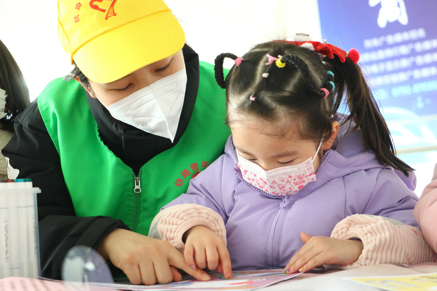 春運首日鐵路青年志愿者為小朋友們講解鐵路安全知識繪本。邱玲攝