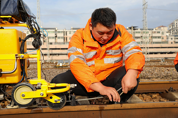 通過手工與儀器相結合方式，協助執機人進行鋼軌傷損的復核工作。中國鐵路南昌局集團有限公司供圖