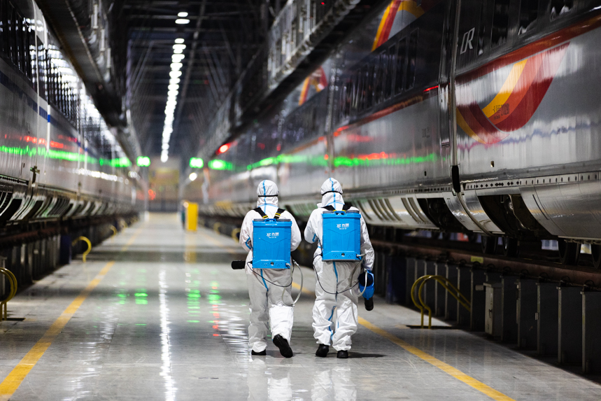 兩名鐵路職工背著消毒噴霧準備對動車組進行消殺。李桐攝