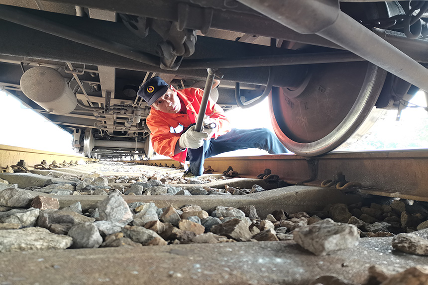 檢車員周志榮正在對轉向架交叉桿進行檢查。王文奇攝。