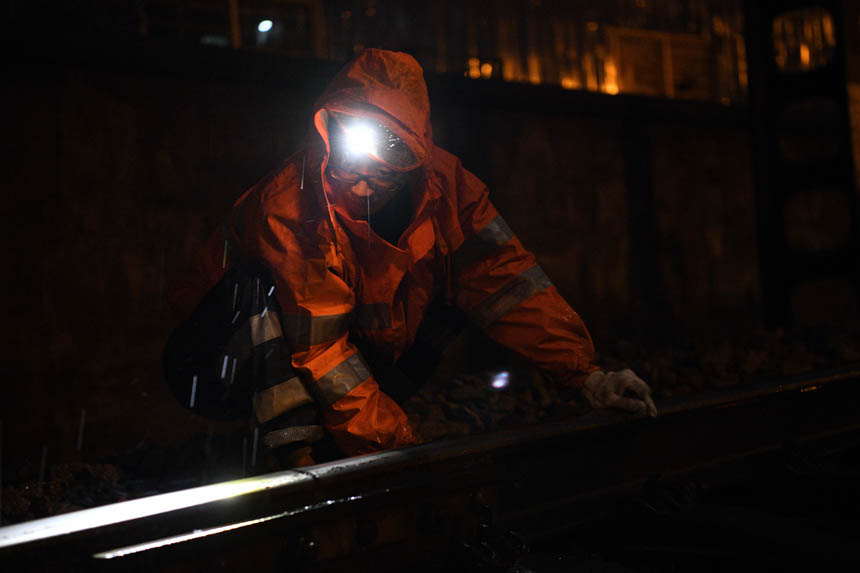 中國鐵路南昌局集團有限公司福州電務段職工在雨中拆除鋼軌側軌道電路電源線。姜振濤攝