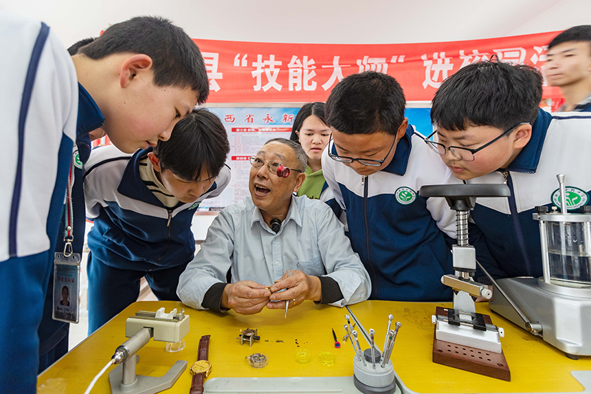 當地鐘表維修大師在給孩子們講解鐘表維修技藝。王惠民攝