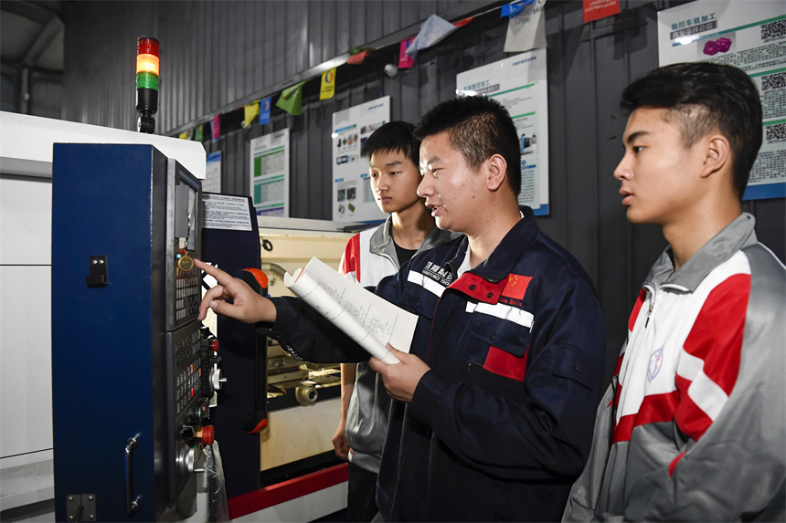 老師在向學生講解數控機床的操作技巧。周亮攝