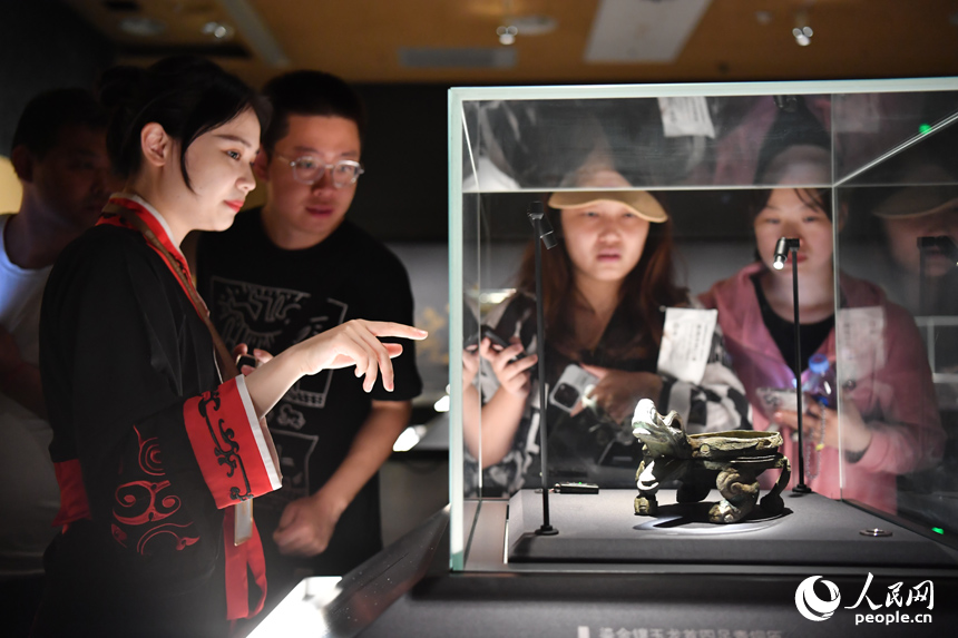 講解員正在為游客講解新展出的鎏金鑲玉龍首四足青銅匜。人民網記者 時雨攝