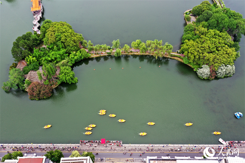 湖面上正在舉行親子龍舟賽，群眾在岸邊加油吶喊。 人民網記者 時雨攝
