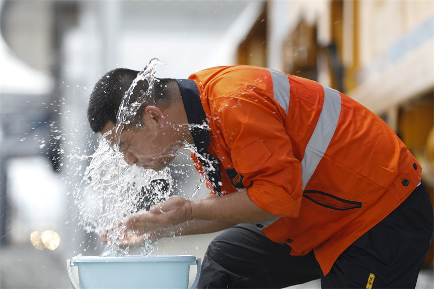 27日中午一名工人在完成車輛養護工作后，洗臉消暑。汪翰攝