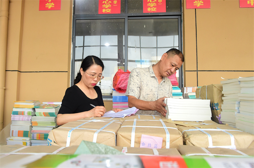 工作人員在清點、登記教材。呂春華攝