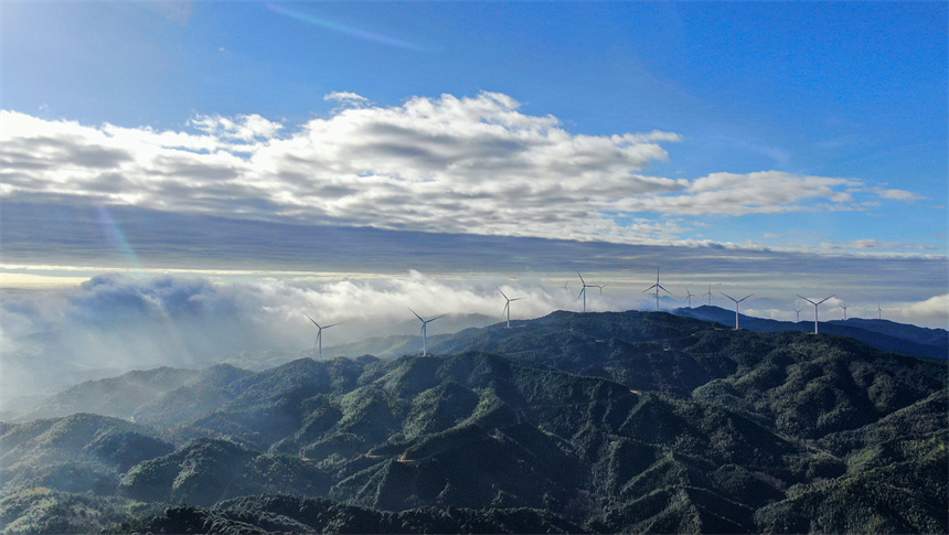 一臺臺風力發電機矗立在群山之巔，蔚為壯觀。詹繼成攝