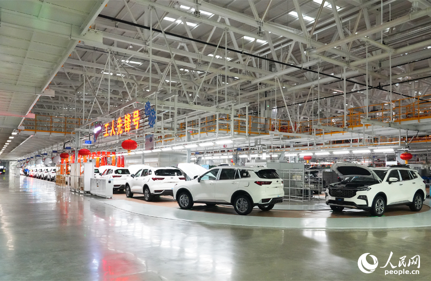 一批剛組裝完成的新車正在燈光通道下接受技術人員的檢測。人民網記者 毛思遠攝