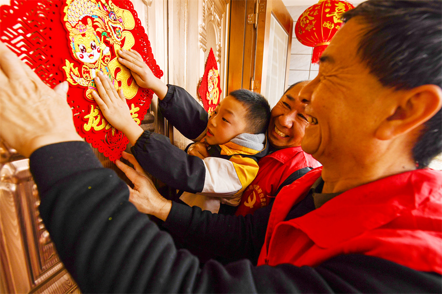 黨員志愿者為村民貼春聯。詹繼成攝 