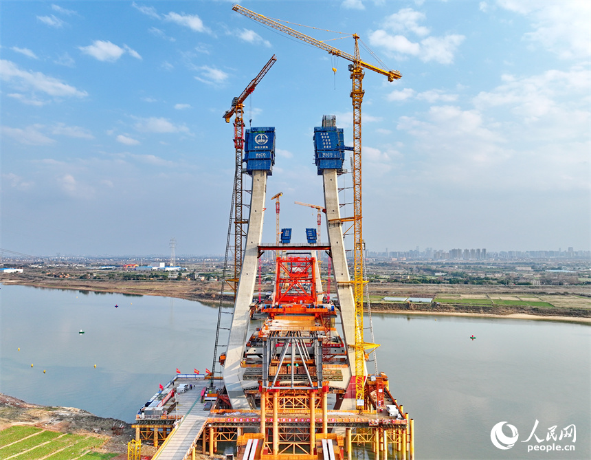 南昌市東湖區揚子洲鎮贛江河畔塔吊矗立，設備有序運轉，工人在隆興大橋項目工地忙碌。人民網 朱海鵬攝