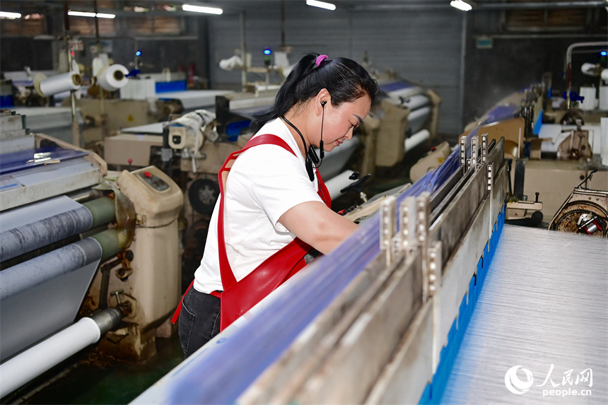 贛州市瑞金經濟技術開發區的一家紡織公司，紡織工人在織造車間加工出口服飾紡線訂單產品。人民網 朱海鵬攝