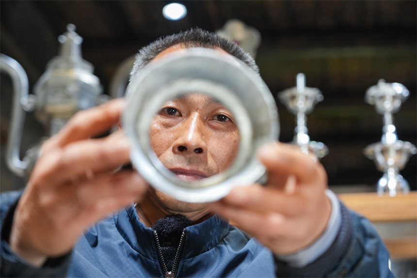 國家級非遺錫雕（蓮花打錫）代表性傳承人劉建強在檢查錫雕的平整度。人民網 孔文進攝