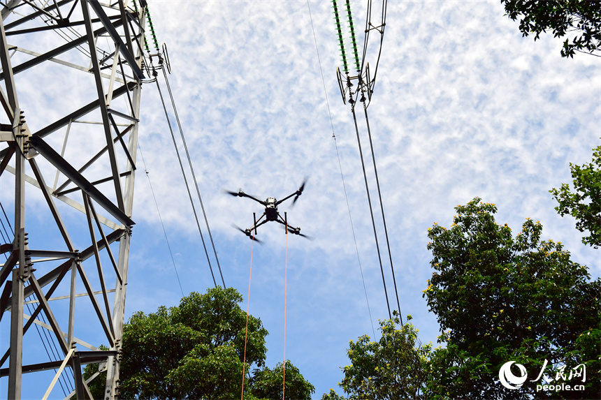 無人機將絕緣繩升空，準備搭設到高空作業點上。人民網記者 時雨攝