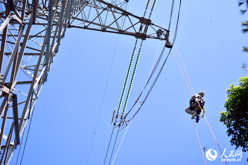 電網檢修工通過“小飛人”向消缺作業點攀升。人民網記者 時雨攝
