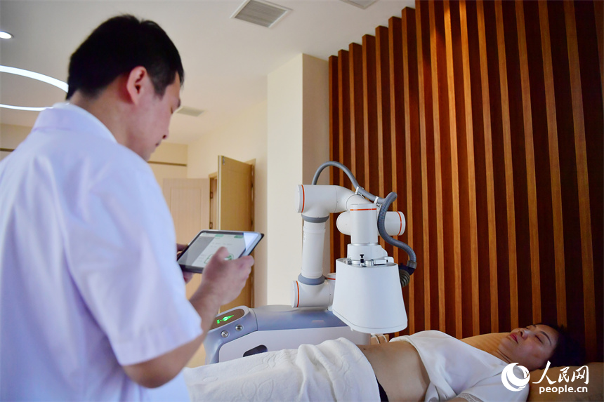 江西中醫藥大學附屬醫院的醫生正通過平板電腦上的App操作熱敏灸機器人，對病人進行熱敏灸的治療。人民網記者 時雨攝