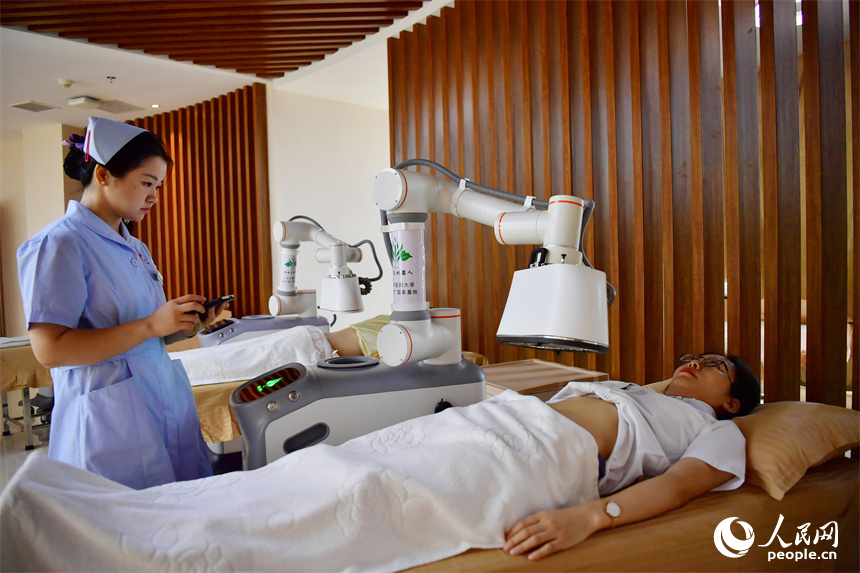 江西中醫藥大學附屬醫院的護士正通過平板電腦上的App操作熱敏灸機器人，對病人進行熱敏灸的治療。人民網記者 時雨攝