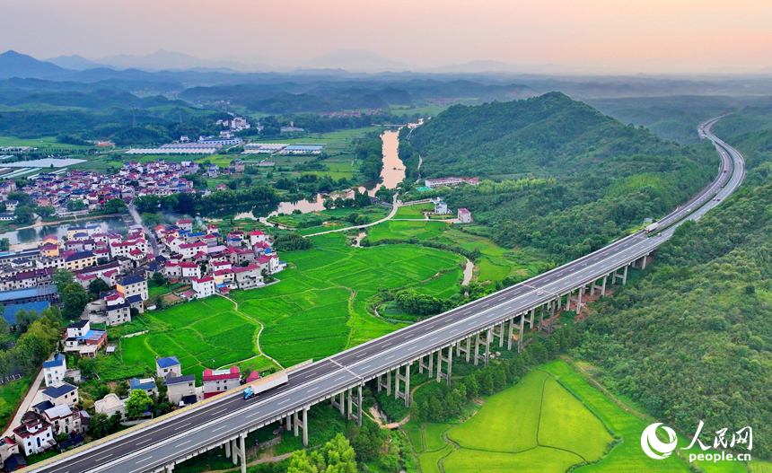 德興市張村鄉界田村，集鎮農房規劃建設有序，高速公路車輛馳騁，與連綿青山、蜿蜒河流、連片稻田相映成景。人民網 朱海鵬攝