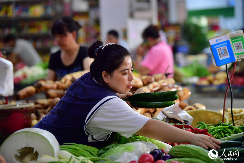 在江西省南昌市紅谷灘區沁園農貿市場內，攤主正在把蔬菜整理歸類。人民網記者 時雨攝