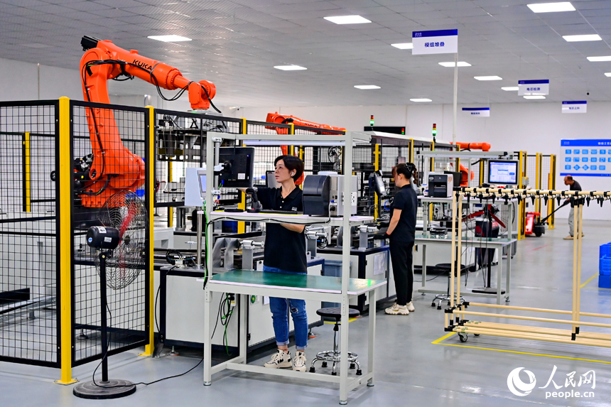 撫州市南豐縣智能制造產業園的一家儲能技術有限公司，智能機械臂來回運轉，工人在車間內忙碌。人民網 朱海鵬攝