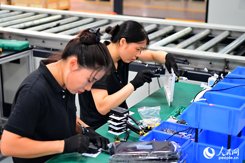 撫州市南豐縣智能制造產業園的一家儲能技術有限公司，智能機械臂來回運轉，工人在車間內忙碌。人民網 朱海鵬攝