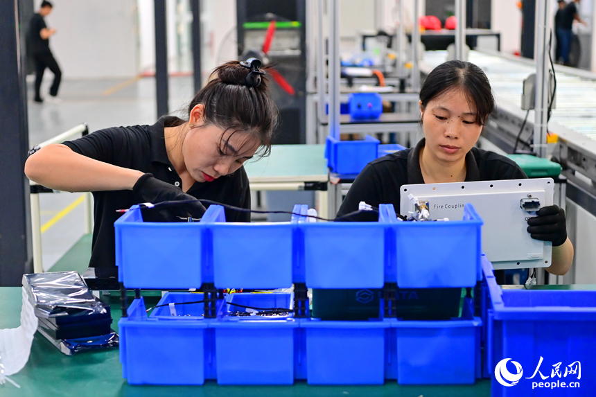 撫州市南豐縣智能制造產業園的一家儲能技術有限公司，智能機械臂來回運轉，工人在車間內忙碌。人民網 朱海鵬攝