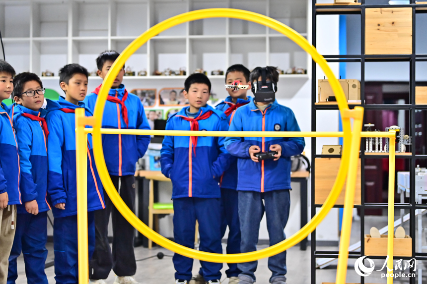 撫州市宜黃縣鳳岡鎮第一小學科普趣味課上，小學生們在操控航模無人機。人民網 朱海鵬攝