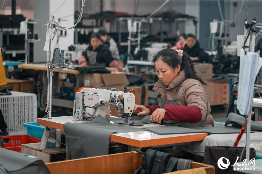 工人們正在縫合行李箱里布。人民網 涂詩軒攝