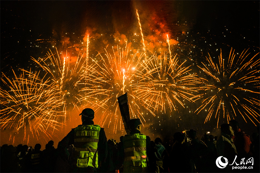 煙花在夜空中綻放，人群在光影間交錯。 人民網 涂詩軒攝