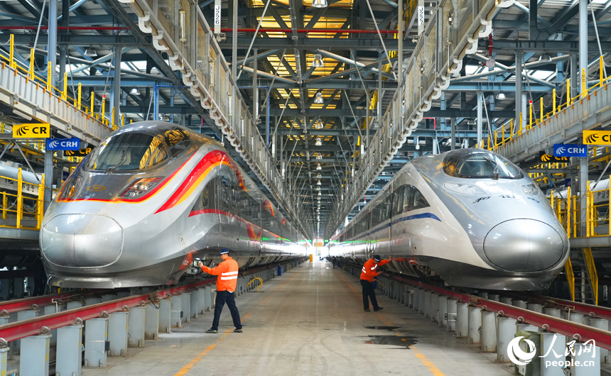 機械師在對復興號智能動車組和和諧號動車組兩側進行巡檢作業。人民網記者 毛思遠攝
