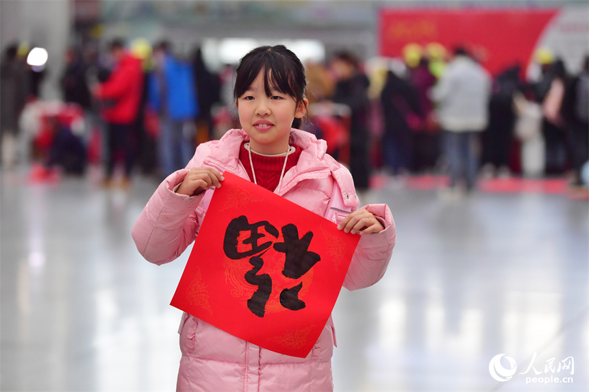 一名小乘客開心展示領取到的“?！弊?。人民網記者 時雨攝