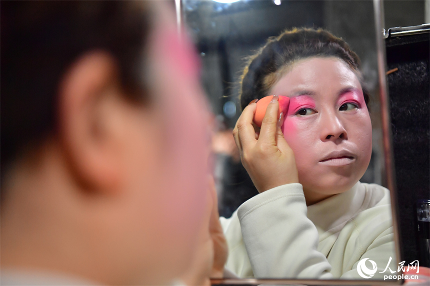 臨時搭建的劇團后臺里，劇團演員正對著鏡子化妝。人民網記者 時雨攝