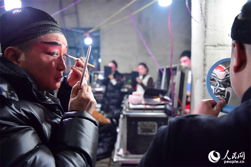 臨時搭建的劇團后臺里，劇團演員正對著鏡子化妝。人民網記者 時雨攝