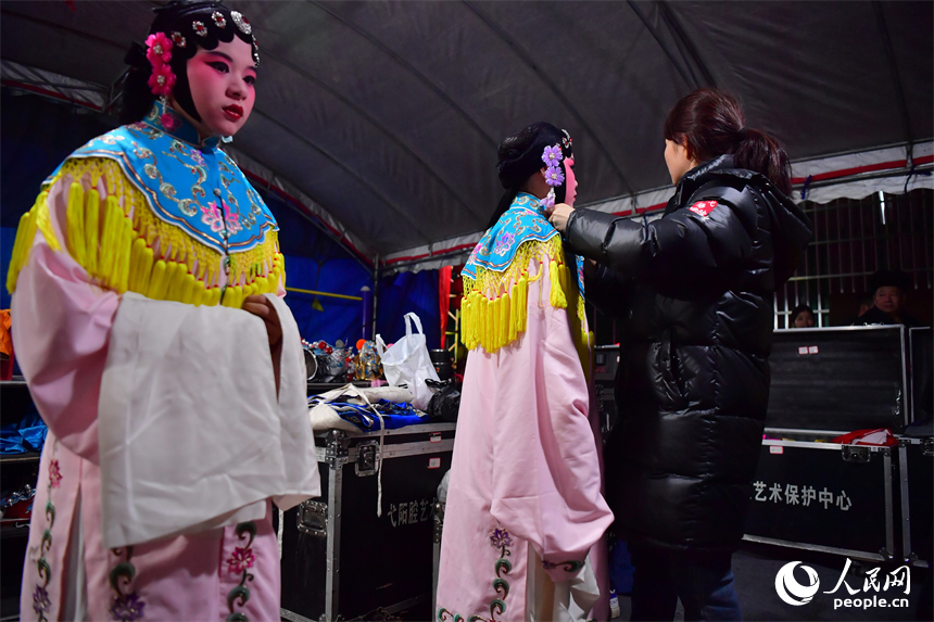 臨時搭建的劇團后臺里，劇團演員正為年輕一代的演員穿戴演出服飾。人民網記者 時雨攝