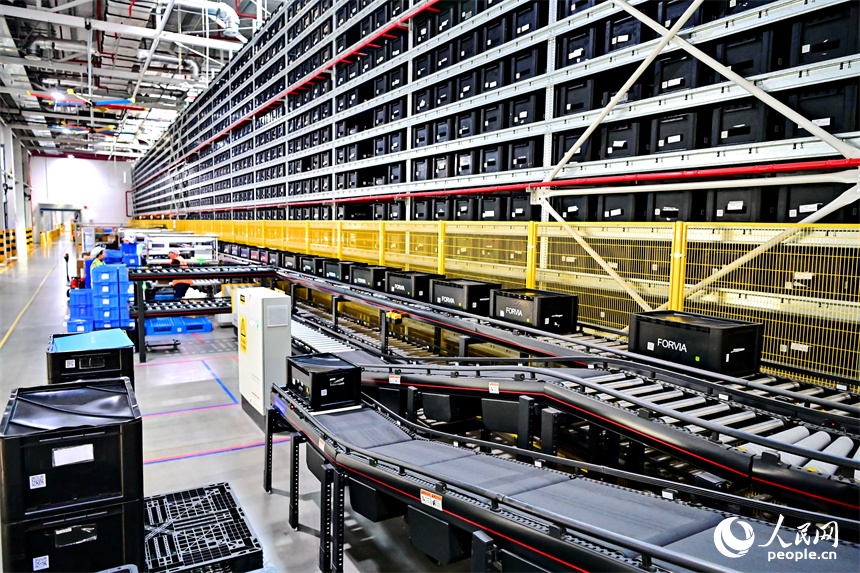 豐城市高新技術產業園區的一家汽車電子企業內，AGV運輸車來回運轉有序作業，工人在加工車載電子產品。人民網 朱海鵬攝