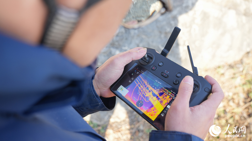 江西送變電公司輸電運檢分公司九江巡檢站檢修人員正在操作無人機對導線進行測溫。人民網 孔文進攝