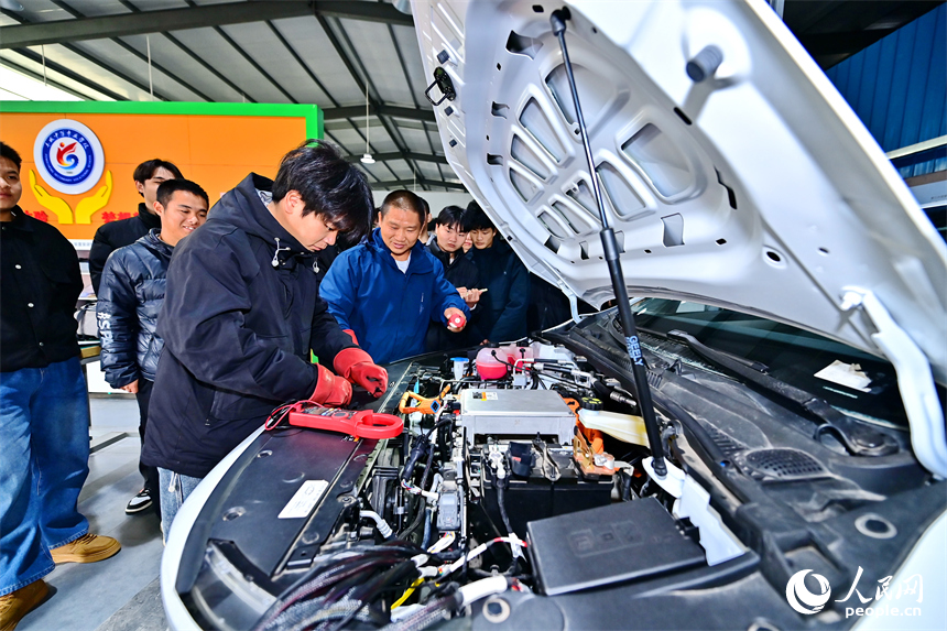 新能源汽車運維專業學生在老師的指導下學習新能源汽車電池包檢修技術。人民網 朱海鵬攝