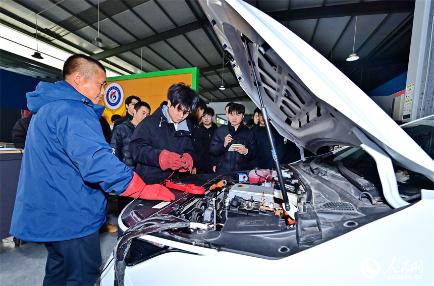 新能源汽車運維專業學生在老師的指導下學習新能源汽車電池包檢修技術。人民網 朱海鵬攝