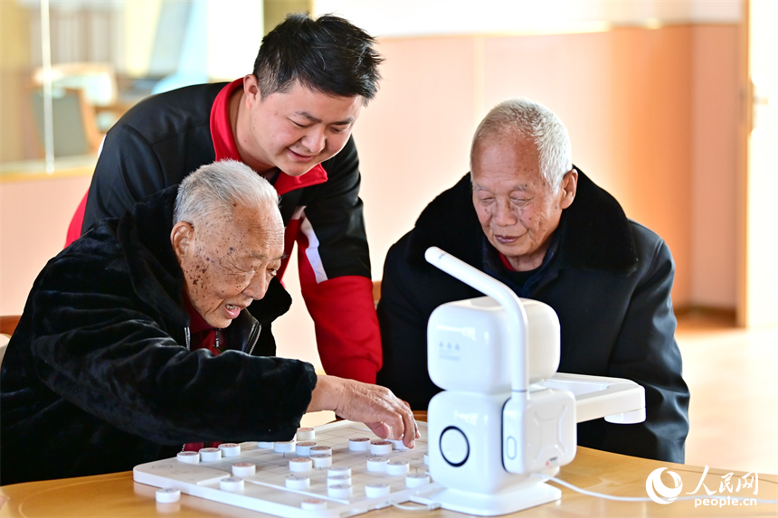 贛州市南康區蟠桃園老年公寓，男護工在教老人與智能機器人下象棋。人民網 朱海鵬攝
