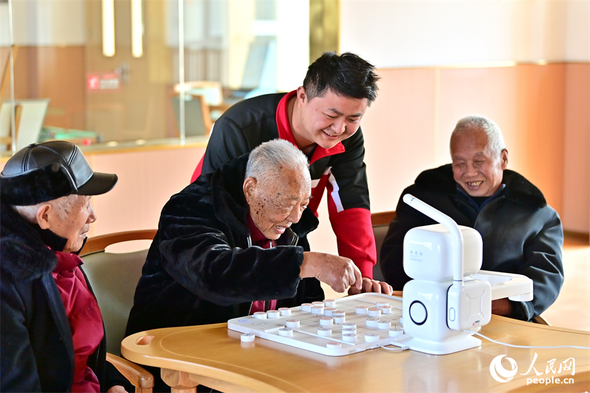 贛州市南康區蟠桃園老年公寓，男護工在教老人與智能機器人下象棋。人民網 朱海鵬攝