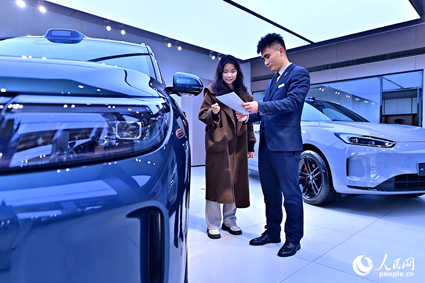 撫州市臨川區的一家國產新能源汽車銷售公司展廳，顧客在了解選購車型并咨詢汽車“以舊換新”補貼政策。人民網 朱海鵬攝