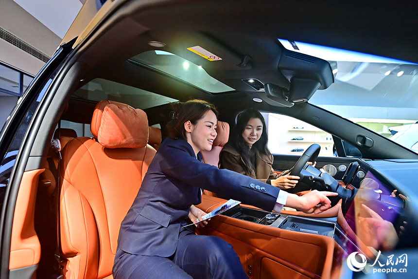 撫州市臨川區的一家國產新能源汽車銷售公司展廳，銷售人員在向顧客介紹車型的智駕功能。人民網 朱海鵬攝