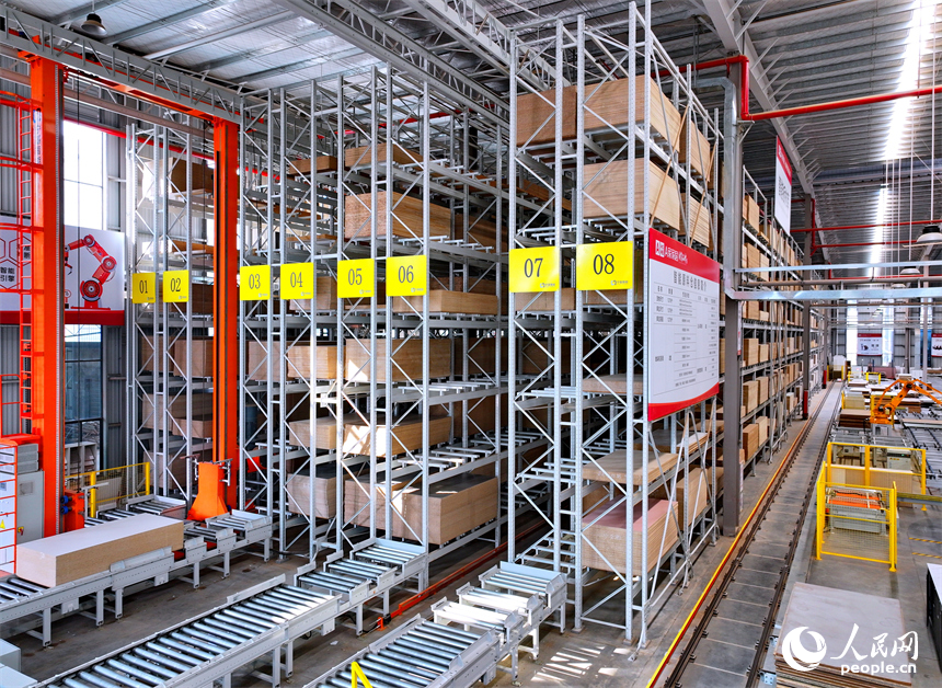 南康區的一家全屋定制家具生產企業智能制造車間內，自動導引車和堆垛機在智能原料倉來回存取板材。人民網 朱海鵬攝