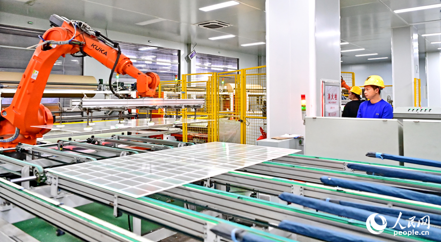 贛州市定南縣的一家新材料有限公司智能制造車間內，機器人手臂在來回循環作業，工人忙著加工光伏玻璃面板。人民網 朱海鵬攝